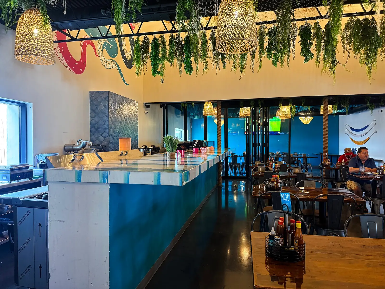 The raw bar with the octopus mural and hanging ferns